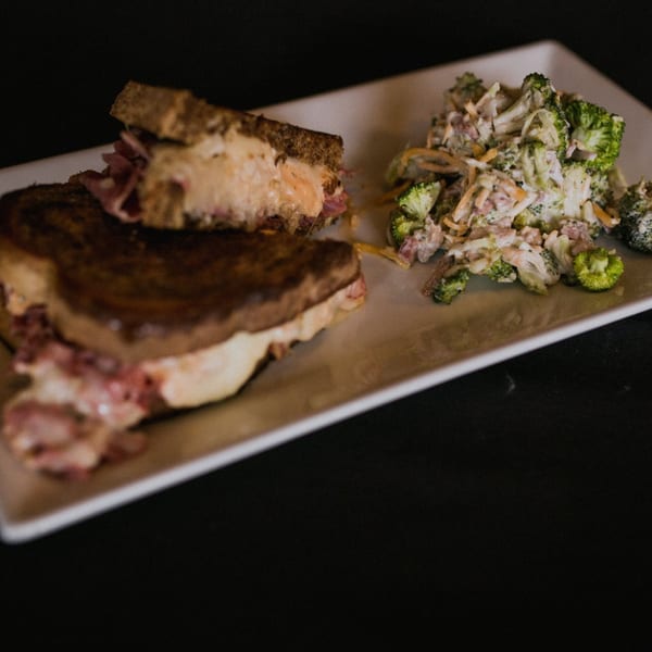 Doolittle's Reuben sandwich with melted cheese and pastrami, served with a side of broccoli salad.