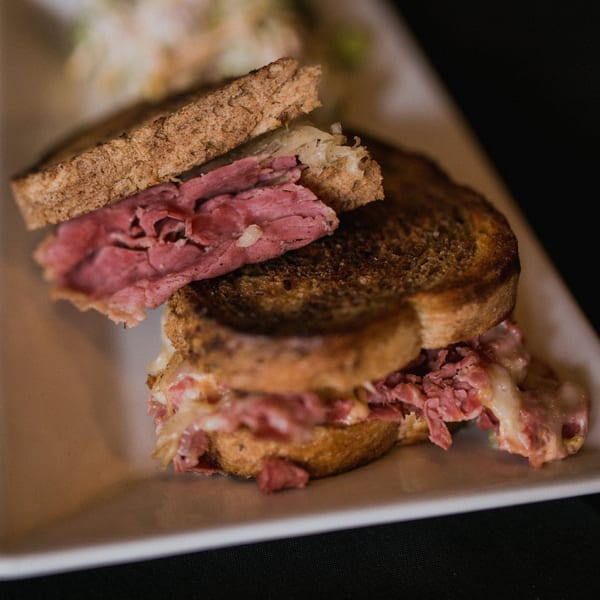 Close-up of a Doolittle's Reuben sandwich with corned beef, sauerkraut, and melted cheese on toasted rye.