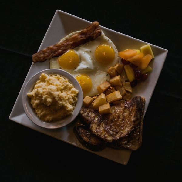Doolittle's American breakfast with eggs, bacon, French toast, home fries, fruit, and grits.