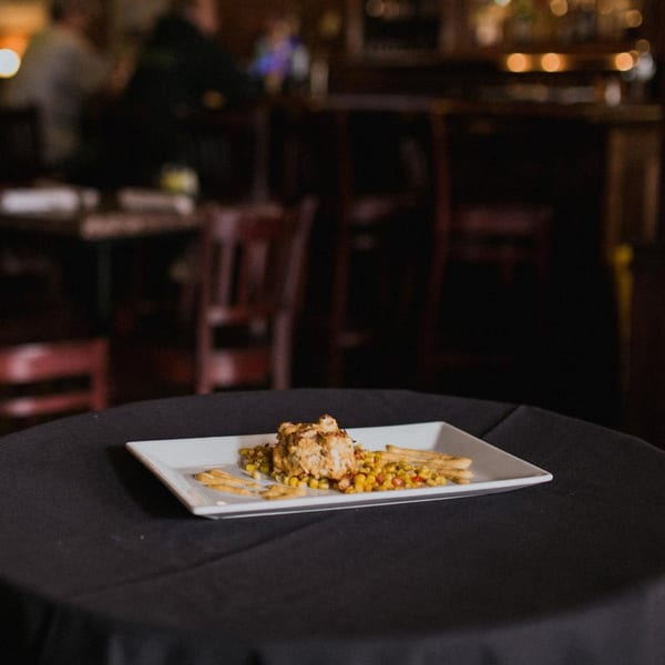 Doolittle's American cuisine: a crab cake with corn and fries on a white plate in a dimly lit restaurant.