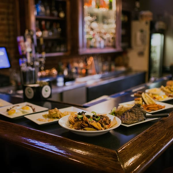 A variety of Doolittle's American dishes, including nachos, steak, and eggs, arranged on a dark bar.