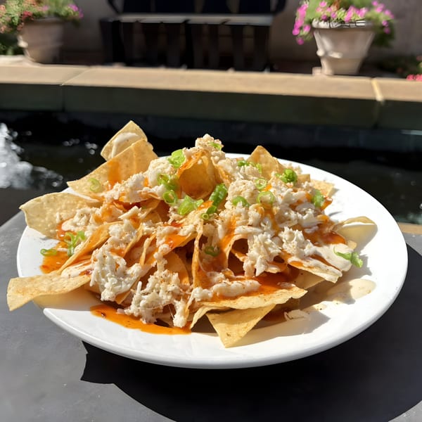 Doolittle's crab nachos with white sauce, orange drizzle, and green onions on a patio.